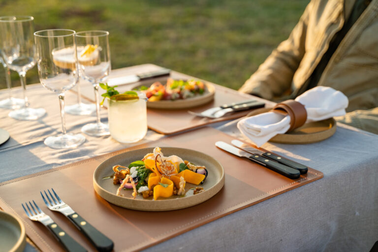 Serene evening at a luxury tented camp, lanterns lit, guests dining under the stars in the Serengeti.